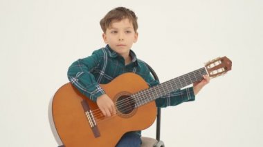 Küçük çocuk büyük klasik gitar çalıyor. Ağır çekimde kapat