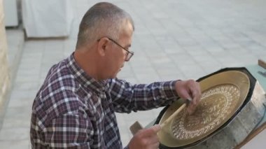 Buhara ustası kalıpları tepsiye oyuyor. Yavaş çekim