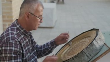 Buhara ustası kalıpları tepsiye oyuyor. Yavaş çekim