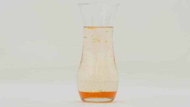 白い背景のガラス花瓶のオレンジ溶岩ランプ効果 スローモーション — ストック動画