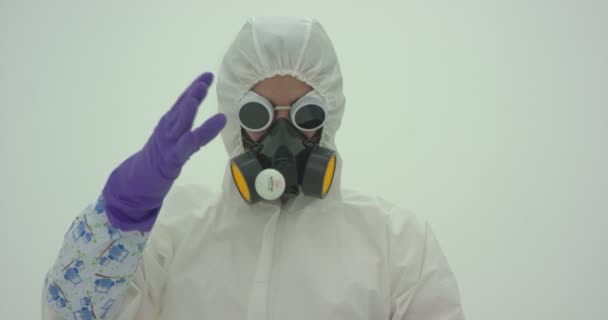 白い化学保護スーツの男とガスマスクは ヘアドライヤーから熱い空気の助けを借りて彼の前にホバーピンポンボールをリリースします カメラを閉めろ スローモーション — ストック動画