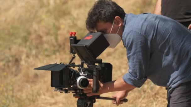 デニムシャツのカメラマンは 自然の中で赤いカメラで撮影します ぼやけた背景でのクローズアップ — ストック動画