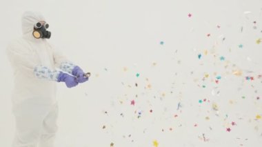 Beyaz kimya koruma giysisi ve gaz maskeli adam parti patlayıcısını patlatıyor. Sol tarafta duruyor. Çerçevede. Beyaz arka planda.