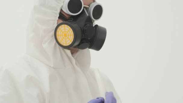 煙が出てくるから白いプラスチックチューブを保持白い化学保護スーツとガスマスクの男の閉じる — ストック動画