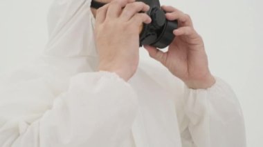 Beyaz kimyasal koruma giysisi giymiş bir adam gaz maskesi takıyor. Beyaz arkaplanda çekilen.