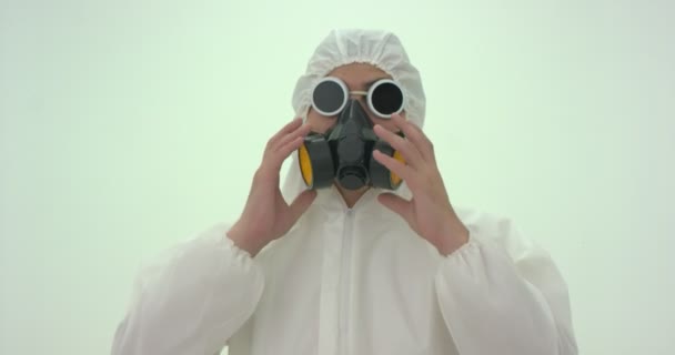 身着白色化学防护服 戴着低矮防毒面具的男子 其头部朝上朝右 戴上防毒面具 过了一会儿 他又把面具放下了 — 图库视频影像