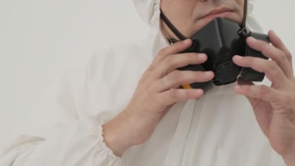 ガスマスクを身に着けて白色の化学防護服を着た男の閉鎖 白地に撮られた — ストック動画