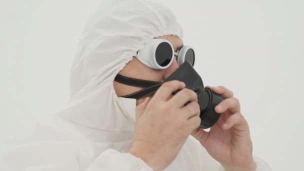 身穿白色化学防护服的人戴上防毒面具 用白色底片拍摄 — 图库视频影像
