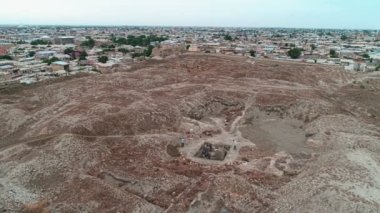 Buhara Kalesi 'nde çalışan arkeologların olduğu bir arkeolojik alan. İHA 'nın panoramayı vuruşunu kaydedip çalışan insanların üzerinden uçuyor. Bulutlu bir günde çekilmiş.