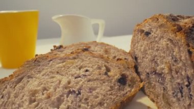 Dilimlenmiş çavdar ekmeğinden, üzerinde bir fincan çay, bir kase salata, beyaz süt sürahisi, sarı kupa ve biraz da bal olan beyaz yemek masasına zoom yap.