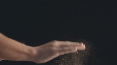 Erkek ellerinin un sallamasını yakından çek. Siyah bir arkaplanda çekilmiş.