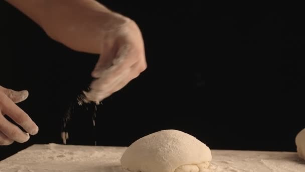 男士们的手在烤面团上撒些面粉 粗糙的东西躺在木制桌子上 用黑色底片拍摄 — 图库视频影像