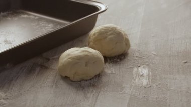 Erkek eller, un serpiştirilmiş ahşap masadan bir parça hamur çıkarırlar. Siyah arkaplanda çekilen.