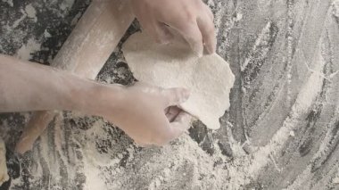 Erkek eller ahşap bir tahta üzerinde merdane kullanarak hamuru rulo haline getirirler. Bir sonraki rulo için hazırlanma alanından ziyade un serpiştirirler. Erkek eller, tahta bir raptiye ile hamuru yuvarlarlar.