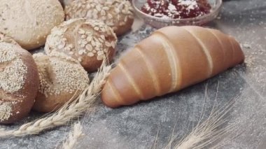 Ahşap masada farklı taze fırınlanmış Hollanda ekmeği türlerinin yakın çekimi var. Kamera ileri geri hareket ediyor.