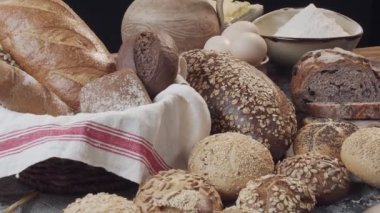 Ahşap masada farklı türde taze Hollanda ekmeği var. Kamera ileri geri hareket ediyor.