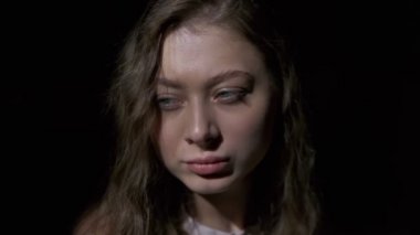 Uzun açık kahverengi saçlı, gri gözlü, beyaz bardaktan zevk alarak kahve içen bir kızın yakın çekimi. Siyah bir arkaplanda tam yüz olarak çekilen