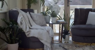 İki koyu menekşe koltuk ve üzerine saksılar ve kitapların konulduğu yuvarlak kahve masası olan odadan çıkmanın köşesi. Diğer yerlerde saksılarda bir sürü yeşil bitki var.