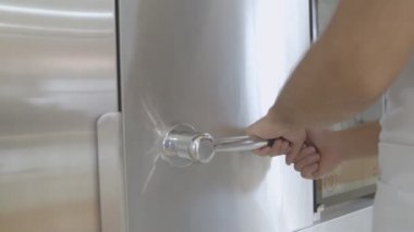 Fırıncıların elleri, büyük bir fırının kolunu ve metal kapısını çevirir ve el arabasında fırın tepsileriyle taze pişmiş ekmek görürüz.