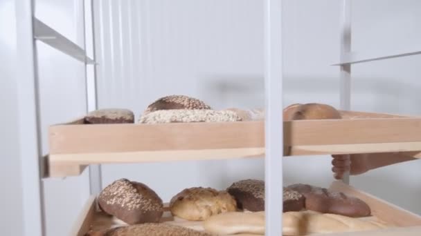 收集的新鲜烘焙面包由一辆装有木制货架的购物车通过面包店运送 慢动作 — 图库视频影像
