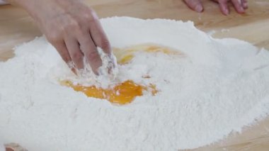 Tahta masadaki un yığınına yumurta karıştırıp hamuru yoğurmak. Yavaş çekim