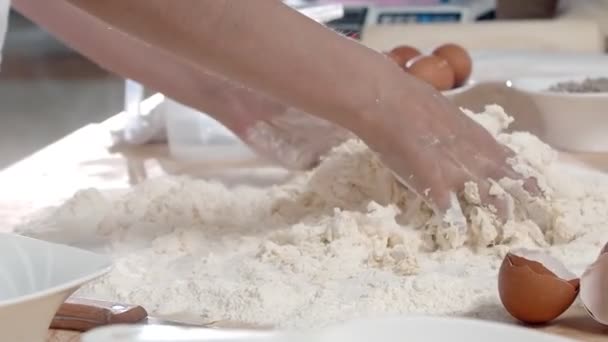 木製のテーブルの上に小麦粉の山に卵を攪拌し 生地をこねるのクローズアップ スローモーション — ストック動画