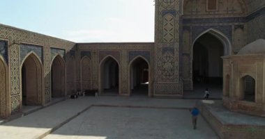 İnsansız hava aracı antik Lyab-i Hauz kompleksinin avlusunda turistlerle birlikte uçuyor. Eski Buhara, Özbekistan. Hava Görünümü.