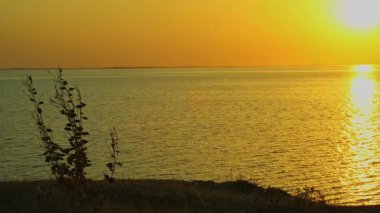 Gün batımında nehrin arka planına karşı yeşil tepeler. Bulutlu bir yaz akşamı. Gerçek zaman.