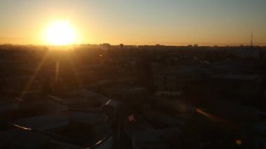 Şehrin üzerinde gün batımı. Bulutlu bir yaz akşamı. Ufuktaki tepeler ve dağlar