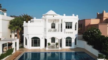 İHA mavi bulutsuz bir gökyüzünün arka planında yüzme havuzu olan özel bir Arap villasının etrafında uçuyor. Hava Görünümü