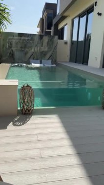 Güneşli bir günde Dubai 'de özel bir villanın arka bahçesinde küçük bir yüzme havuzu ve kanepesi var. Dışarıda ağır çekim.