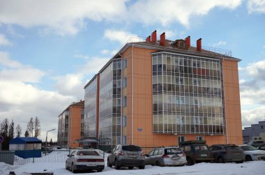 Taezhny, Krasnoyarsk Bölgesi, Rusya - 29 Mart 2020: Arabalar kışın yeni tuğla apartman binalarının yakınlarındaki bir kar yığınının çitlerine park edildiler.