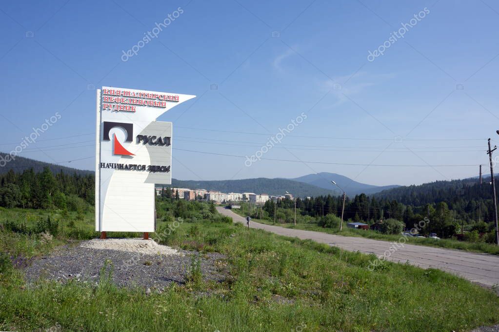 Belogorsk, Kemerovo region, RF - June 26, 2016: Stella with the Rusal logo stands at the entrance to a mountain village on a sunny summer day against the backdrop of wooded mountains.