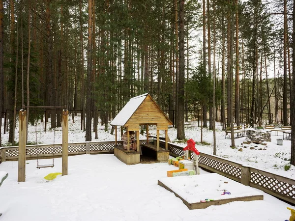 Télen Fenyvesek Között Hótakaró Borítja Játszóteret Kis Faházzal Homokozóval Hintával — Stock Fotó