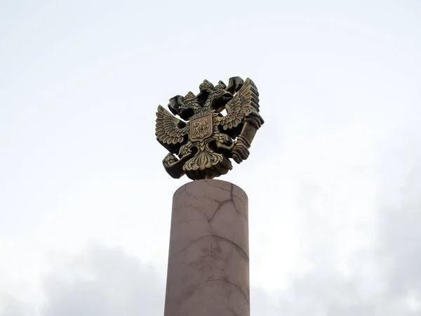 ロシアの紋章は 空に対する柱の上に青銅で鋳造されたロシア連邦 1993 の公式の国家シンボルです — ストック写真