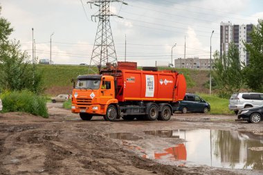 Krasnoyarsk, Krasnoyarsk Bölgesi, RF - 20 Temmuz 2021: Üzerinde Rusça bir yazı bulunan bir çöp kamyonu - Geri dönüşüm şirketi, bulutlu bir yaz gününde bir su birikintisi etrafında yol alır..
