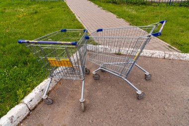 Krasnoyarsk, Krasnoyarsk Bölgesi, RF - 20 Temmuz 2021: Logosu ve hipermarketin adı olan iki boş araba yazın kaldırıma bırakıldı..