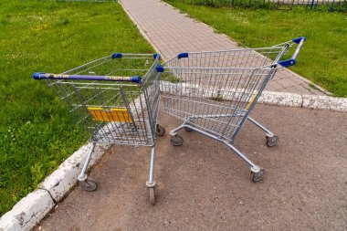 Krasnoyarsk, Krasnoyarsk Bölgesi, RF - 20 Temmuz 2021: Logosu ve hipermarketin adı olan iki boş araba yazın kaldırıma bırakıldı..