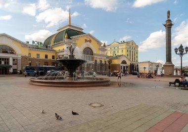 Krasnoyarsk, Krasnoyarsk Bölgesi, RF - 19 Temmuz 2021: Güvercinler şehrin ana tren istasyonunun önündeki istasyon meydanında çeşmeli ve bir yaz günü kentin sembolü olan bir sütunla yürüyor.