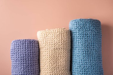 Çok renkli ketenler, pamuk banyosu ve kaplıca havluları pembe arka planda kıvrılmış.