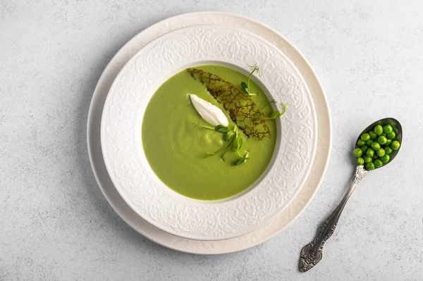 Homemade soup puree of green peas, coconut milk with tuil and cheese quenelle