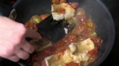 Kadın eli, geleneksel Sicilya balığıyla domatesli bir spatula serer.