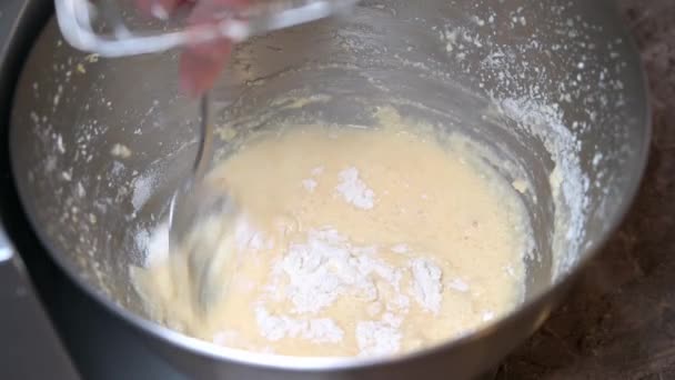 A nő beleönti a lisztet a keverőtálba a tésztával, és kanálból keveri. — Stock videók