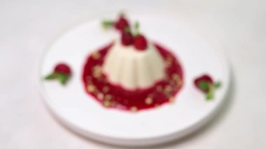 Panna cotta üzerinde yumuşak ahududu ve beyaz tabakta nane