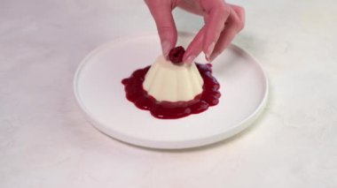 Kadınların elleri panna cotta 'ya ahududu üzümü serer.