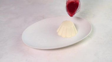 Kadınların elleri oval beyaz tabağa ahududu şurubu döker.