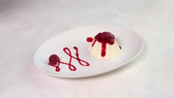 Femme main dépose des baies de framboise et feuille de menthe à panna cotta — Video