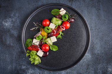 Domates, salatalık, bel biberi, zeytin ve siyah tabakta beyaz peynir ile taze Yunan salatası.