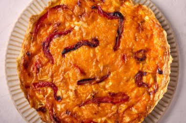 Tavuklu ev yapımı kiş turtası, kurutulmuş domates, açık arkaplanda çedar peyniri.