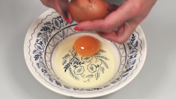 Kobieta rozwala jajka o talerz nożem i bije je widelcem. — Wideo stockowe